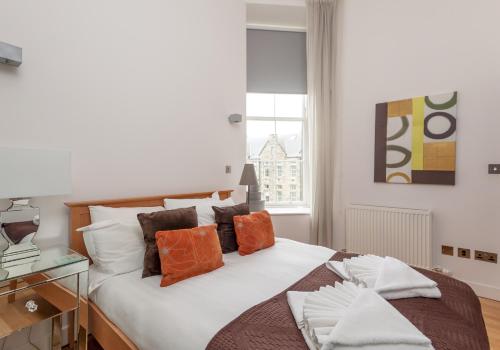 um quarto com uma cama com almofadas laranja e branca em The Quartermile Meadows View Residence em Edimburgo