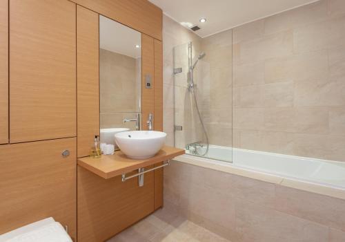 uma casa de banho com um lavatório e uma banheira em The Quartermile Meadows View Residence em Edimburgo