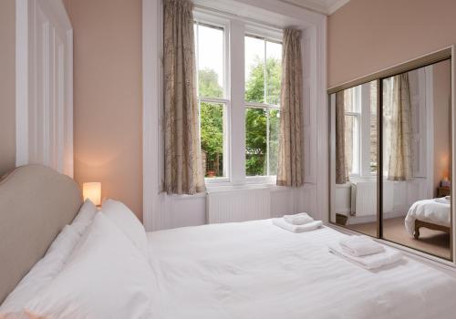 a white bedroom with a large bed and a window at The Coates Gardens Residence in Edinburgh