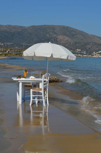 a table and chair on the beach with an umbrella at Parthenis Beach, Suites by the Sea in Malia