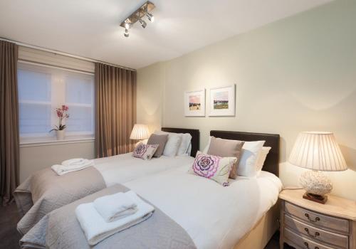 two twin beds in a bedroom with a window at The Botanist Apartment Edinburgh Old Town 2 Bedroom Lift Parking previously The Parkgate Residence in Edinburgh