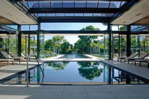 a swimming pool in a building with chairs and a swimming pool at Vineyard Hotel in Cape Town