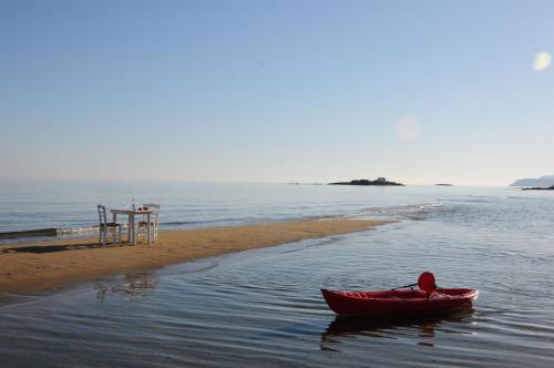 a red boat in the water next to a beach at Parthenis Beach, Suites by the Sea in Malia