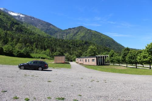 a car parked in a gravel parking lot with mountains in the background at Chaletpark Petzen in Feistritz ob Bleiburg