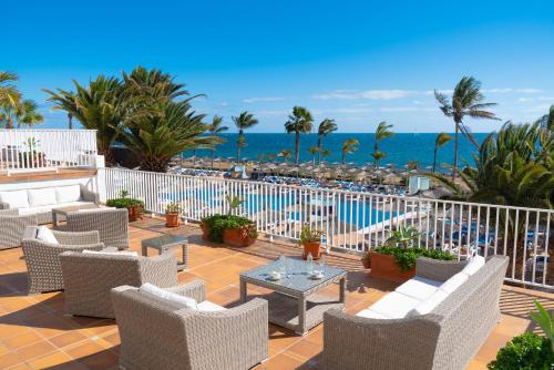 a patio with chairs and a table and the ocean at VIK Hotel San Antonio in Puerto del Carmen