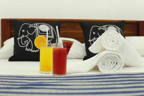 a glass of juice and towels on a bed at Amsterdam Tourist Rest in Anuradhapura