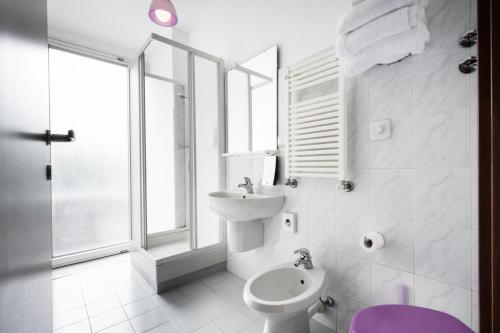 Baño blanco con lavabo y aseo en Hotel Nologo, en Génova