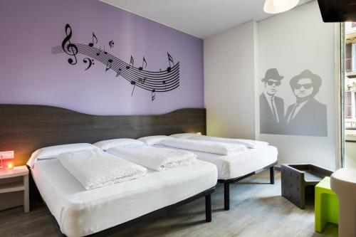 3 camas en una habitación con notas musicales en la pared en Hotel Nologo en Génova