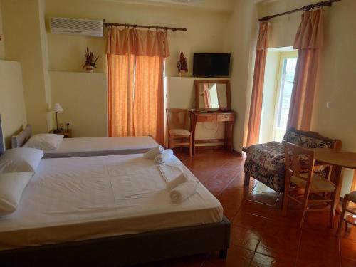 a bedroom with two beds and a chair and a television at Atlantis in Ermoupoli