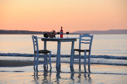 a table with two chairs sitting on the beach at Parthenis Hotel & Suites in Malia