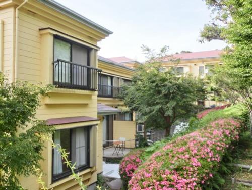 a yellow building with pink flowers in front of it at 伊道荘園 in Futo