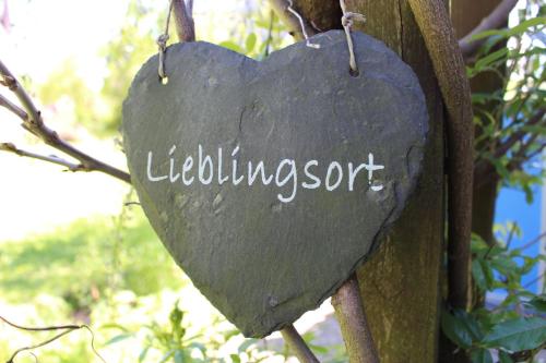 un signo en forma de corazón colgando de un árbol en Ferienwohnung Paula en Bitz