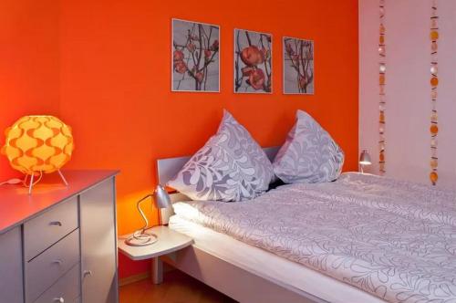 um quarto com uma parede laranja e uma cama com almofadas em Ferienwohnung Paula em Bitz