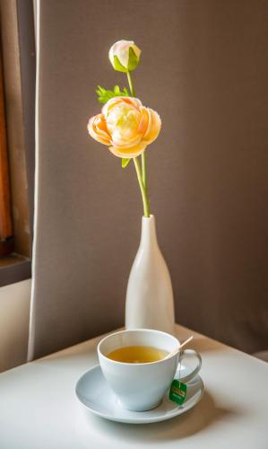 a cup of coffee and a vase with a flower at Sandmoen Bed & Breakfast, Free Parking in Trondheim