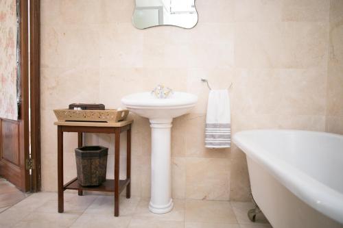 a bathroom with a white sink and a bath tub at Villa Pascal Guest House in Durbanville