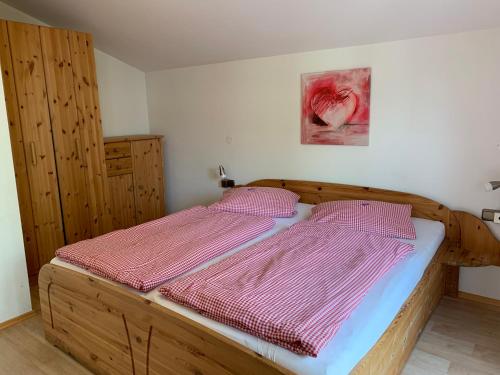 1 dormitorio con cama de madera con sábanas rosas en Landhaus Alpensee 2, en Oberstdorf