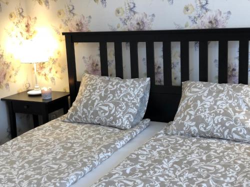 a bed with two pillows next to a table with a lamp at Tulipán Villa Panzió in Szolnok