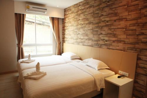 a bedroom with two beds and a brick wall at Golden City Rayong Hotel in Rayong