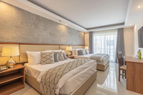 a hotel room with two beds and a desk at Dun Gorg Guest House in Marsaxlokk