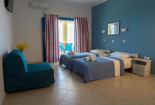 a hotel room with two beds and a chair at Hotel Loukas Vrachos in Paralia Vrachou