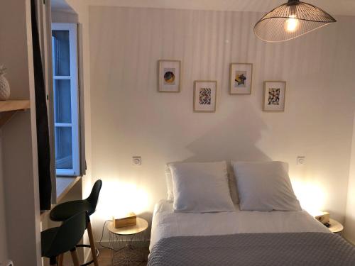 a white bedroom with a bed and a chair at Maison Simonenia in Saint-Jean-Pied-de-Port
