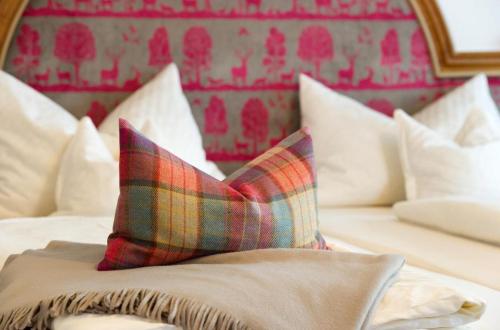 a bed with a plaid pillow on top of it at Hotel Alpenkönig in Oberstaufen