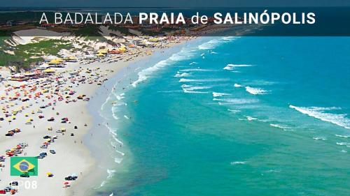 Una playa con multitud de gente y el océano. en Condomínio Raízes Marina, en Salinópolis