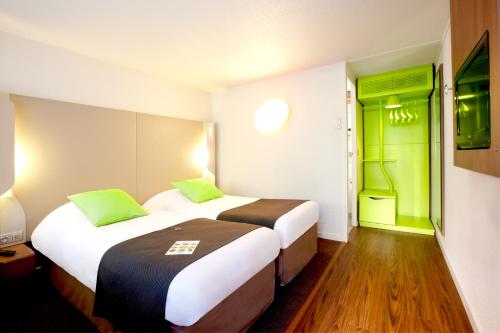 two beds in a hotel room with green walls at Campanile Biarritz in Biarritz