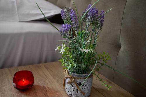 a vase with purple flowers on a table with a candle at Hotel Niku in Tirana