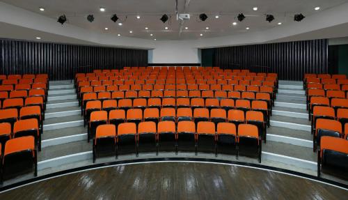 an empty auditorium with orange seats and lights at King Solomon Hotel Tiberias in Tiberias