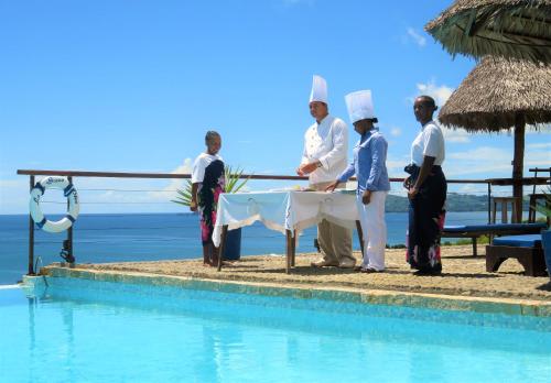a group of people standing around a table next to a pool at Le Grand Bleu in Andilana