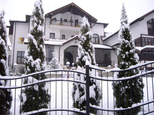 a house with snow covered trees and a fence at Casa Domneasca in Curtea de Argeş