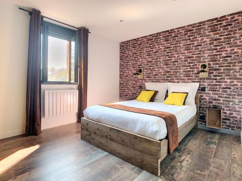 a bedroom with a brick wall and a bed with yellow pillows at Le Bord de Sèvre in Saint-Laurent-sur-Sèvre