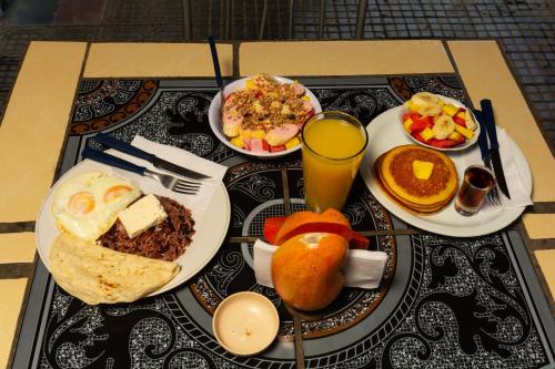 una mesa con platos de desayuno y un vaso de zumo de naranja en Hostal Lazybones, en León