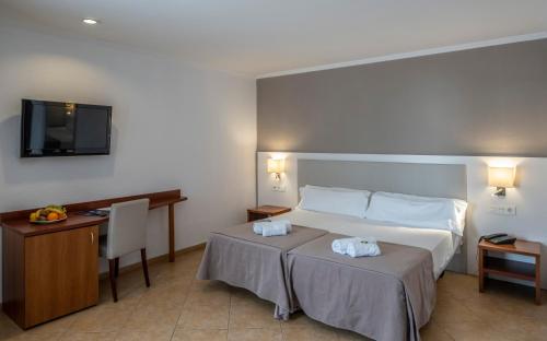 a bedroom with a bed and a desk and a television at Rosamar & Spa 4*s in Lloret de Mar