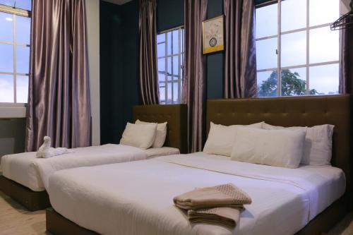 two beds in a bedroom with two windows at The b'Hotel in Kajang