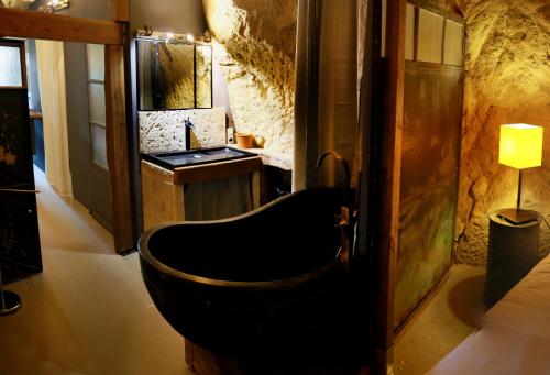 ein Bad mit einer schwarzen Badewanne in einem Zimmer in der Unterkunft La Grotte du Moulin in Noyers-sur-Cher