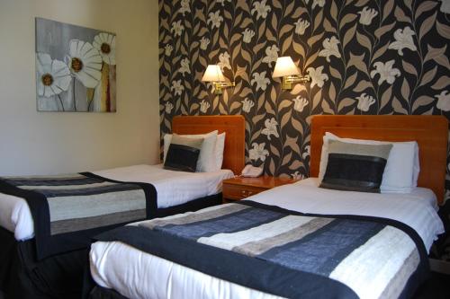 two beds in a hotel room with flowers on the wall at The Tontine Hotel in Greenock