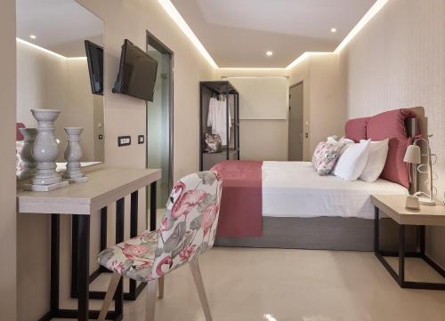 a bedroom with a bed and a desk and a chair at Koukounaria Hotel & Suites in Alykes