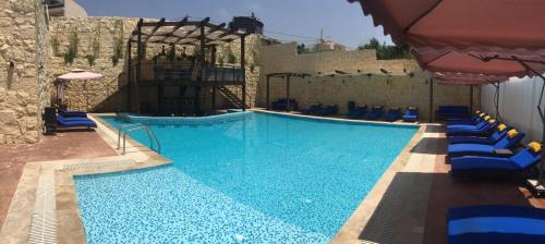 a large swimming pool with blue chairs and an umbrella at Ibiza Hotel in Jounieh