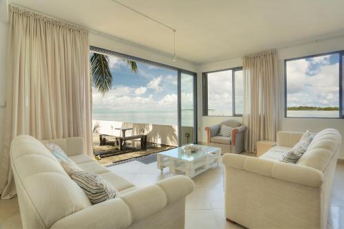 a living room with white furniture and a view of the ocean at Auberge SeaFever in Mahébourg