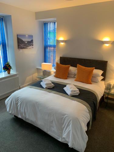 a bedroom with a large white bed with orange pillows at Muir Bank in Muir of Ord