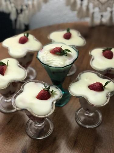 a group of desserts in glass cups with strawberries in them at Halikarnas Pansiyon in Bodrum City