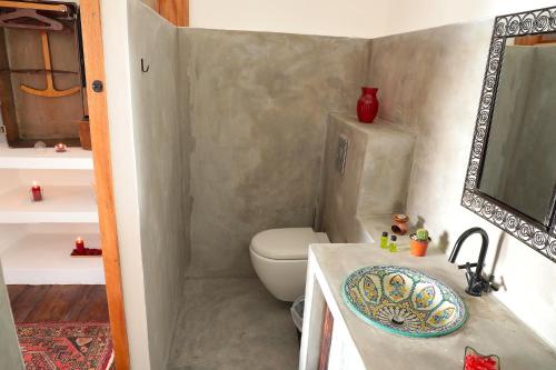 a bathroom with a toilet and a sink and a mirror at Casa Colonial Koenig in São Filipe