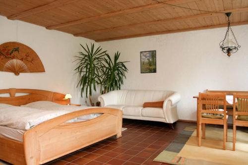 1 dormitorio con cama de madera y sofá en Pension Steiger, en Bad Griesbach