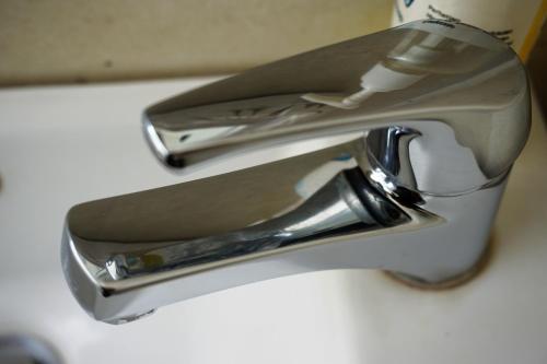 a silver faucet on a white sink at Louto Dmell Villa & Guesthouse in Sanur