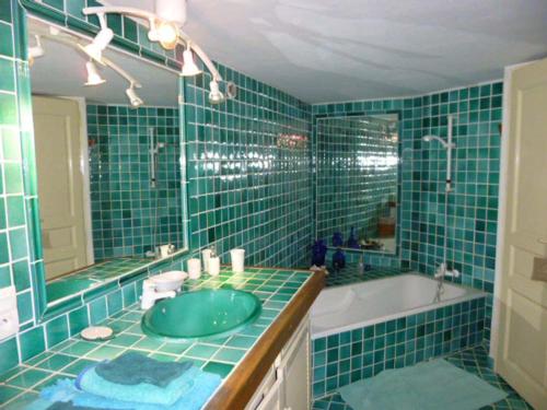 Baño de azulejos verdes con lavabo y bañera en Chambre d'hôtes La Romarine, en Barnave
