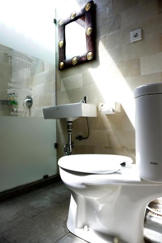 a bathroom with a white toilet and a mirror at Louto Dmell Villa & Guesthouse in Sanur