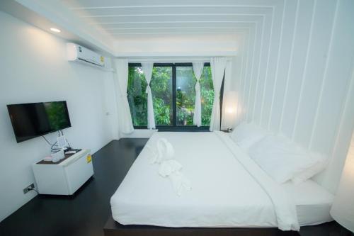 a white bedroom with a large bed and a window at Trat 101 Hotel - SHA Certified in Trat