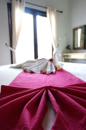 a bed with a pink blanket on top of it at Louto Dmell Villa & Guesthouse in Sanur